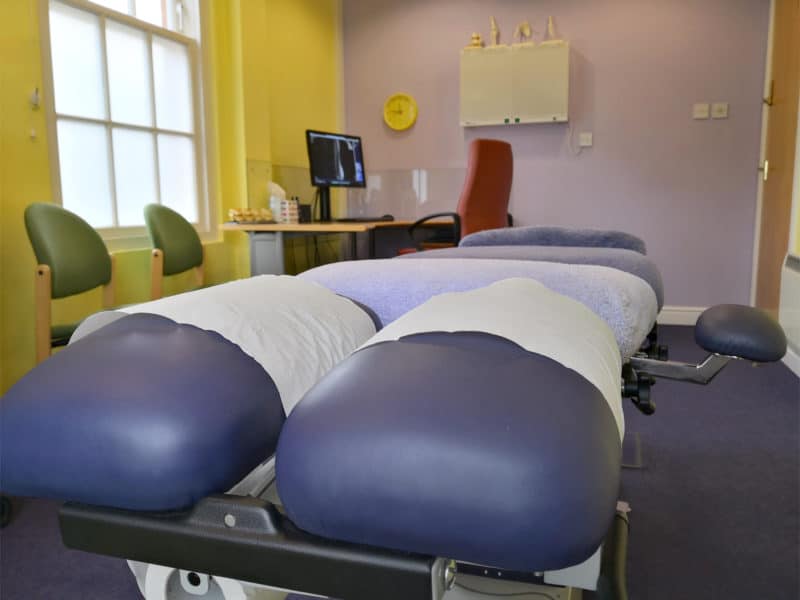 Derby Chiropractors WellBeing Clinics Treatment Room Close up view of one the derby chiropractors treatment benches from the head end in the back ground is a desk with an MRI of a low back visible on the screen